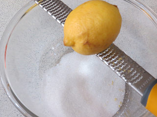 10、法式小甜点【椰蓉柠檬小方】,制做柠檬酱。将砂糖放入碗中，擦入2 个柠檬皮屑