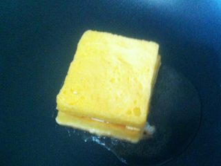 7、芝士火腿西多士,锅烧热，倒入适量的食用油，小火，将制作好的半成品裹上蛋液置入锅中