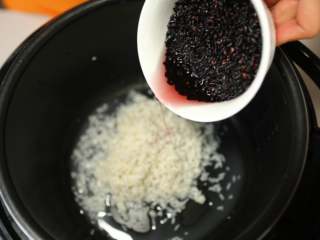 3、美味甜点-芒果黑米甜甜,将泡好的黑米、白糯米一起放入电饭煲中，加入水，按下煮饭键