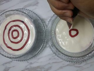 10、蓝莓果酱拉花酸奶,再倒入些酸奶，接着在表面挤上几圈蓝莓果酱