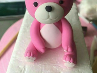 15、翻糖布偶熊--翻糖蛋糕装饰,粘上四肢，在头的下方用扎一个1到2厘米深的孔，插在身体上头。最后搓一个小球球做尾巴按在身体后面就完工喽！