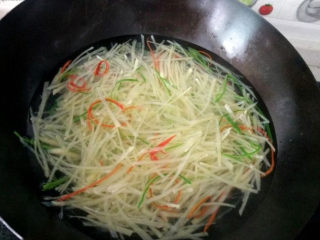 6、这道菜成本就几块钱，比大鱼大肉还好吃！,锅中加入适量的水，水烧开后将土豆丝，青红椒丝下锅一同焯水，断生后即可捞出，切记不能煮太长时间，那样土豆丝就不脆了（这里加入青红椒丝除了可以提