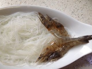 3、蒜蓉粉丝开片虾 ,一小把白粉丝用温水泡软,沥干铺于盘中,将虾展开铺于粉丝上,如图示;