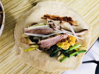 45、老北京春饼,先取一张薄饼，拌豆芽，韭菜、蒜黄、菠菜、白菜、摊鸡蛋、煮白肉、酱肘子、葱丝、炸酱 依次放入！