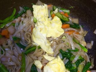 7、炒河粉,加入泡好的米粉和鸡蛋一起翻炒，加入适量盐和酱油，炒拌均匀即可出锅