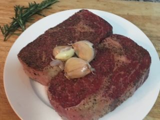 2、迷迭香蒜味肋眼牛排佐栉瓜,牛排两面都抹上盐和黑胡椒粉；蒜头带皮拍扁。