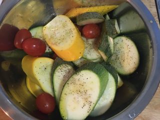 4、迷迭香蒜味肋眼牛排佐栉瓜,将栉瓜片、小蕃茄都装在大盆里，用橄榄油、盐和黑胡椒粉抓匀备用。