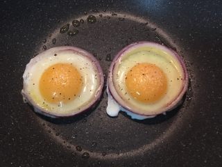 5、迷迭香蒜味肋眼牛排佐栉瓜,不沾平底锅加热后，抹些油，然后放入洋葱圈先稍微煎一下下，接着再缓慢的将蛋打入，并在蛋上撒少许盐和黑胡椒粉调味。