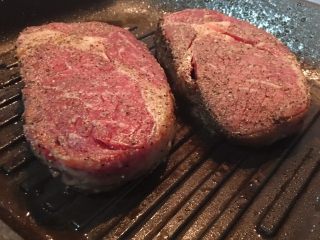 12、迷迭香蒜味肋眼牛排佐栉瓜,原锅再加些橄榄油，改转成中大火，将锅烧热后，放入牛排，ㄧ样是放下后就先不要动，煎个1-2分钟，观察牛排侧边变色的部份如已快到牛排厚度的ㄧ半时，就可翻面。把另一面也同樣方式煎上色。