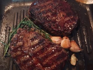 14、迷迭香蒜味肋眼牛排佐栉瓜,接着牛排平放，加入无盐奶油，蒜头和迷迭香增加风味。奶油溶化后，可用小汤匙不停的将烧热的奶油舀起浇在牛排上，直到自己喜爱的熟度。(烦请参考网路上有教学用触感控制牛排熟度的完整图喔）