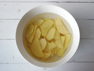 2、【干煸土豆片】 ,将土豆切成0.5厘米厚的片，再放在清水中投洗去淀粉，捞出沥净水待用