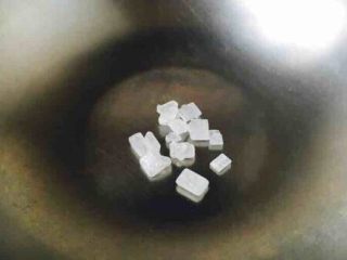 5、莲藕烧排骨（附无水无油炒糖色技巧）,开始炒糖色 锅热了以后改用中火，把冰糖放入锅中。 一般炒色用油炒或者用水来炒，我们既不用油也不用水，我们是直接炒。 这就是无油炒糖色法。