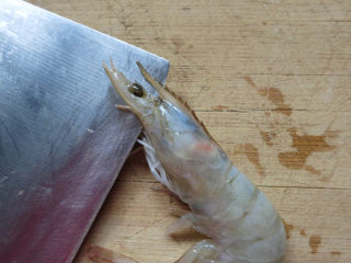 12、翘尾巴的金银蒜蓉开背虾,虾平铺在板上，一手按住虾身，刀从虾头的两眼之间入刀