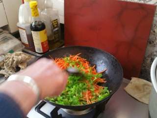 6、家庭鱼香鸡丝,锅中放油烧热，放入胡萝卜丝，青椒丝，煸炒片刻。