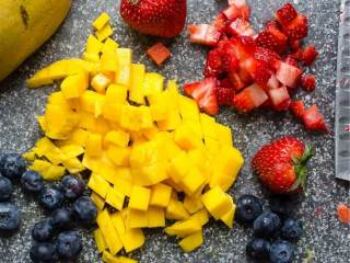 6、热带风椰子朗姆布丁,吃之前一个小时来制作水果沙拉。取一个小碗，混合芒果 （切成小片），草莓 （切成小片），蓝莓 。撒上糖 ，黑朗姆酒 ，翻拌均匀。
