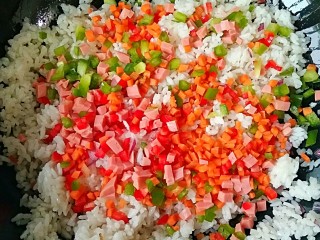 5、波点蛋包饭,然后在放入彩椒，胡萝卜，火腿碎翻炒均匀。