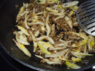 4、蟹味菇春笋肉酱意面,加入备用的蟹味菇和春笋翻炒均匀。