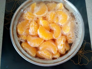 7、橘子罐头,此时，橘子变得膨胀起来了，再调成小火慢慢的煮，偶尔用勺子搅拌一下，以防粘底。