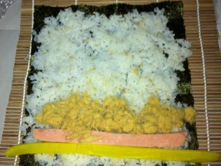 4、家庭版紫菜包饭,米饭打散，撒一点寿司醋，熟芝麻，没有寿司醋撒些许白醋也可以，取一张海苔麻棉向上，米饭均匀的涂在海苔上，放上黄萝卜条香肠鸡蛋条肉松，胡萝卜丝，沙拉酱和辣酱，卷紧，