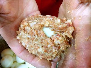 6、做年货 家宴特色秘制龙眼丸子（31个步骤图文详细解释）,用双手轻轻的将肉馅把鸡蛋裹上。