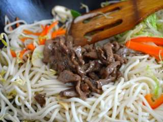 11、牛肉炒面,加牛肉，然后从底部搅拌30秒。 把锅盖上焖一分钟。开盖，加酱油、芝麻油、盐。搅拌均匀，再炒一分钟，起锅。