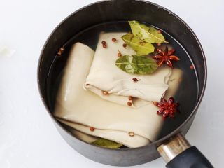 1、凉拌千张,锅里倒进水放进豆腐皮，再放八角、香叶、花椒、盐大火煮开后关火，豆腐皮放在锅里浸泡一小时入味。