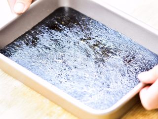 7、黑芝麻麦芽糖,趁热，在桌子上敲动容器，让芝麻糖平整。