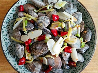 5、酒蒸蛤蜊――快手复刻美味,将锅中爆出香味的葱姜蒜干辣椒(底油不多的话连同底油一起),均匀撒在蛤蜊上。