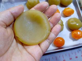 9、广式月饼~莲蓉蛋黄月饼,莲蓉馅在手中捏扁。在包馅的时候，皮可能会粘手，不易把皮往上推，最好是戴一次性手套，比较好操作。