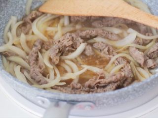 7、日式肥牛饭(完美酱汁配比),洋葱炒到稍微有些变软的时候,倒入煮过的肥牛片,倒入调好的酱汁。稍微翻拌一下帮助牛肉和洋葱更好地吸收汤汁的味道,保持大火就可以。等到汤汁稍微收干,余下少量汤汁的时候关火,这个度自己把握,看个人喜好,喜欢汤汁多一点拌饭的可以早一点关火。