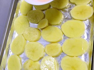 3、烤鲈鱼,把土豆洗净去皮切厚片，平铺于已经铺好锡纸的烤盘，并刷一层葵花籽油