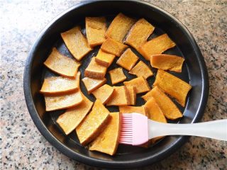 10、蜂蜜烤南瓜,取出南瓜,先在南瓜底面刷上一层蜂蜜。