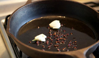 1、抓饭,预先反复淘洗大米,尽可能洗去大米表面淀粉,冷水浸泡30min。预热铸铁锅,油略起烟放入花椒和拍扁的蒜煎香,蒜呈金黄色后捞出备用,花椒变黑后取出。因带皮不易软嫩,另将羊肉切块焯姜水后略留汤汁高压锅上压20min。葡萄干浸水泡软