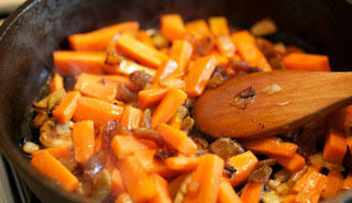 4、抓饭,放入胡萝卜和葡萄干一起翻炒至胡萝卜软嫩,入少许糖