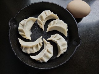 2、抱蛋煎饺,准备鸡蛋和饺子，将饺子均匀的放入锅内。