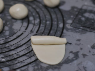 9、蛋黄酥,将包好油酥的面团擀成牛舌状，两头对折，竖起来擀成长条，由上往下卷起来，全部卷好后盖上保鲜膜松弛15分钟，将松弛好的油面卷对折，按扁，再把面皮做大点，将豆沙蛋黄放在中间，包裹起来，收口封严，稍微搓圆