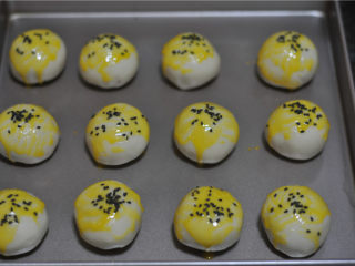 10、蛋黄酥,放入不沾烤盘中，刷上蛋黄液，在顶部撒适量黑芝麻