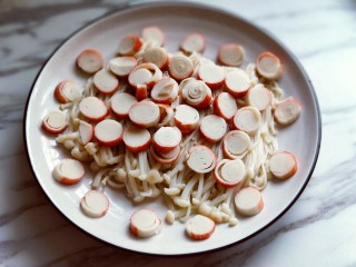 6、新年必备的双味儿蟹肉蒸金针菇,将切好的蟹肉棒片放在金针菇上面。