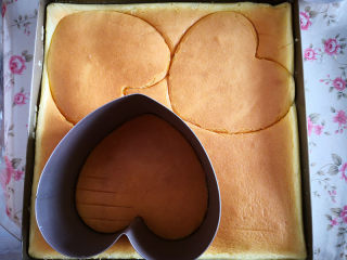 6、樱桃慕斯,用慕斯圈在蛋糕片上按出需要的形状，这个心形慕斯圈按出三片蛋糕片，慕斯圈放在六寸披萨盘里，取出一片蛋糕片放在慕斯圈底部，再把其余两片蛋糕片用手撕去一圈，大约1厘米的宽度，