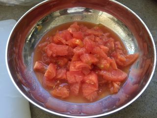 3、番茄茄丁肉酱拌面,番茄切掉根部,然后切番茄丁。切好的番茄和汁水,一起放入碗里,备用。