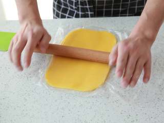 6、抹茶/原味蝴蝶酥,面团松弛期间，将要裹入的116g黄油隔保鲜膜用擀面杖压成厚薄均匀成长方形的薄片