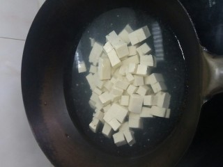 3、宅吃辣豆腐,切豆腐。切成一块一块的。这个地方不方便拍,因为会使用手刀。即一手托着豆腐一手往锅里扔切好的豆腐块。