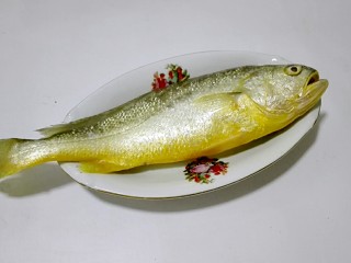 1、披红戴绿的蒜香红辣椒蒸黄鱼,黄鱼用刀刮去鱼鳞