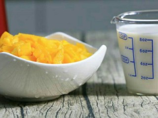 2、芒果奶昔,将芒果丁倒入惠尔宝料理机容杯内加入牛奶，盖紧杯盖。