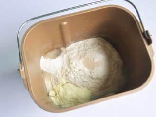 1、玉米沙拉三明治, 把液体材料放入面包桶中，面粉铺在上面，对角分别上放上盐、糖、奶粉，在面粉中间挖一个小坑，放上酵母，启动面包机揉面程序10分钟。