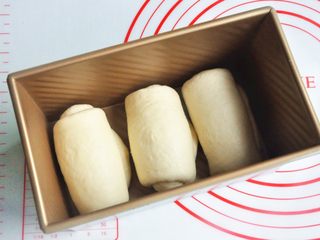 8、玉米沙拉三明治,再次擀开成长条状，面团卷起，收口朝下放置，将面团放入吐司模。