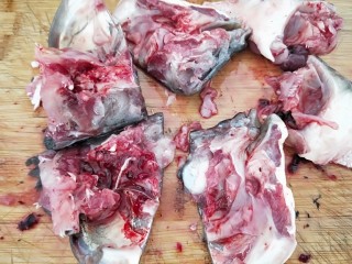 3、家常酸菜鱼,鱼头剁成块，温心提示，要戴围裙哟，不然溅一身，鱼骨，鱼头放入盆中加葱姜蒜片，料酒淹制半小时备用。