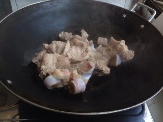 6、剑花猪骨汤,炒菜锅烧热加少许油和姜片,加入猪骨,炒一下。