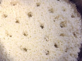 3、足球饭团,上蒸屉蒸，为了方便糯米熟得快，我们可以在上面用筷子戳上几个小洞。