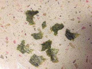 7、足球饭团,摊好保鲜膜，上面撒上撕碎的海苔。